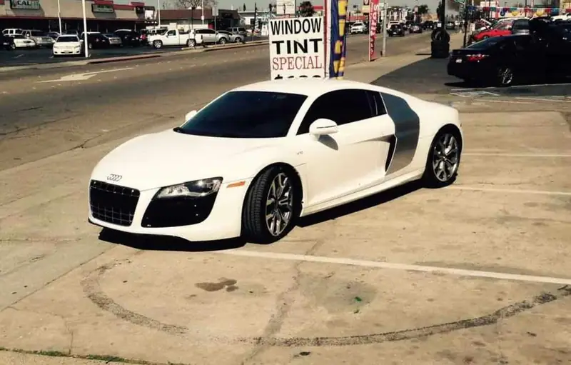 White Audi R8 with a window tint special sign behind it