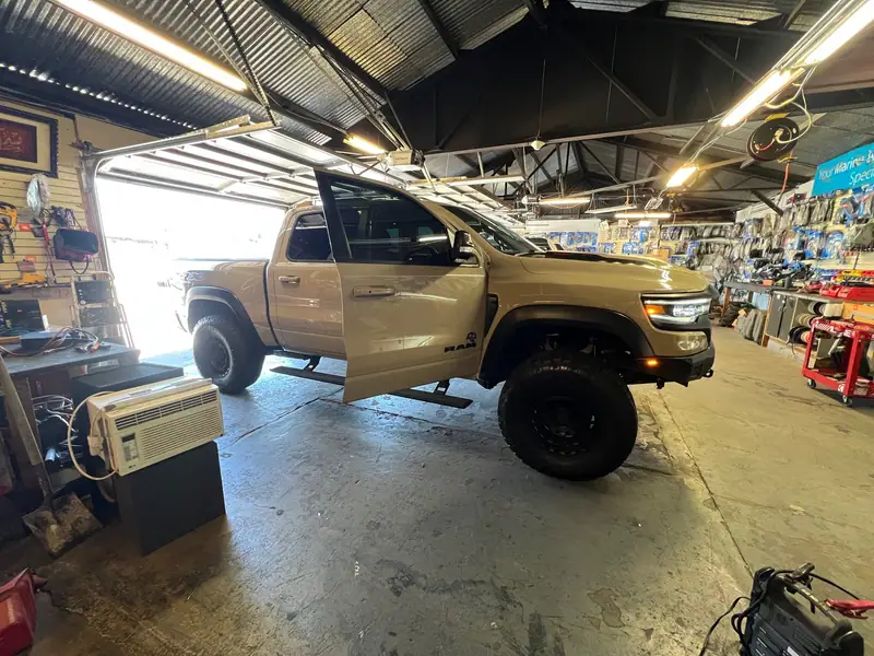 Tan pickup truck with the door open in the installation bay